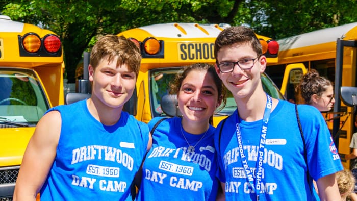Three staff smiling by buses
